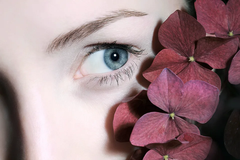Imagen de un ojo de una mujer junto a pétalos de flores