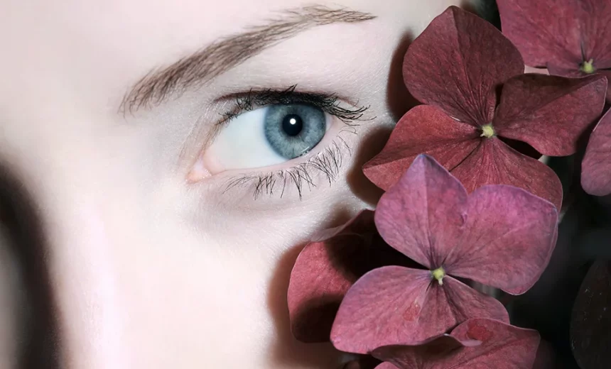 Imagen de un ojo de una mujer junto a pétalos de flores